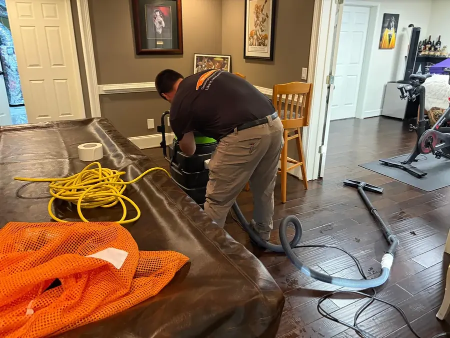 Restoration technician extracting standing water from a flooded Four Oaks, NC home